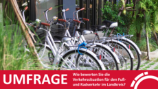 Vier Fahrräder stehen in einem Fahrradständer zwischen Grünpflanzen
