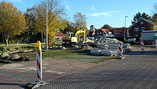 Rot-weiße Barken sperren den Baustellenbereich ab, in dem ein Bagger steht und sich mehrere Sandhaufen und Betonrohre befinden.