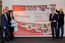 Mitarbeiter der Freiwilligenagentur, KVHS und Harm-Uwe Weber vor dem Plakat der Freiwilligenagentur