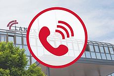 Telefongrafik vor einem Foto des Auricher Kreishauses