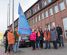 Gruppenfoto vor der Fahne zum Tag gegen Gewalt an Frauen