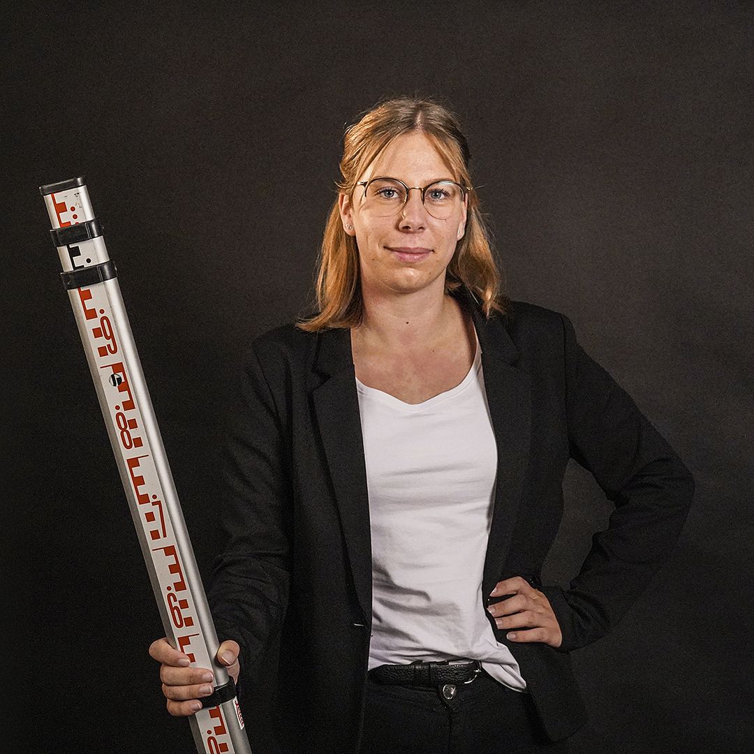 Auzubildende zur Bauzeichnerin hält eine Teleskopnivellierlatte