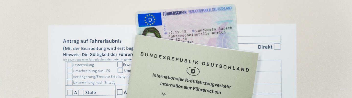 Antragsformular für eine Fahrerlaubnis mit einem Autoschlüssel, einem deutschen Kartenführerschein und einem internationalen Führerschein (Bundesrepublik Deutschland) auf weißem Hintergrund.