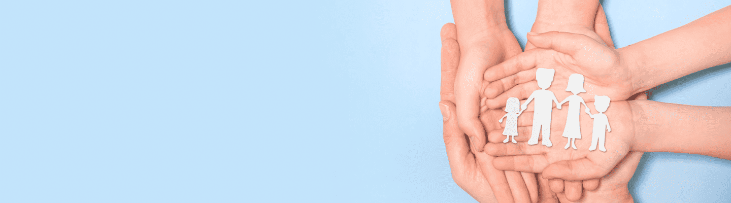 Symbolbild: 6 Hände von zwei Erwachsenen Person und einem Kind halten eine Papiersilhouette einer Familie die sich die Hände hält.