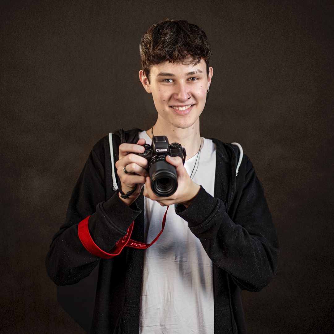 Auzubildener zum Mediengestalter hält eine Fotokamera