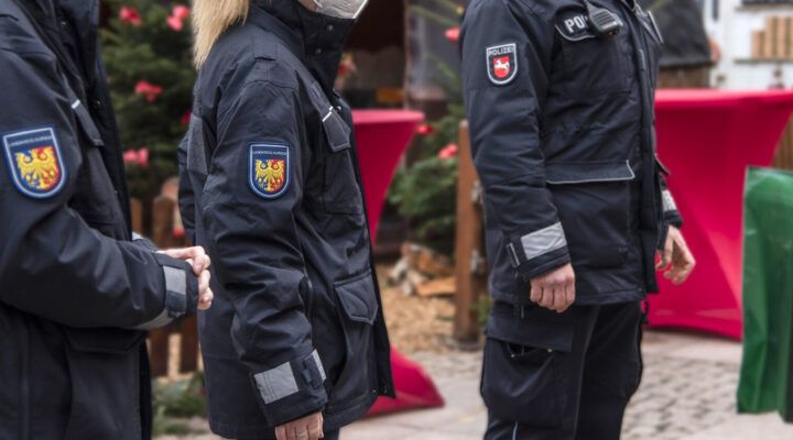 Mehrere Einsatzkräfte des Landkreises Aurich stehen nebeneinander bei einer Veranstaltung im Freien. Auf ihren dunklen Jacken ist das Wappen des Landkreises Aurich zu sehen. Im Hintergrund befinden sich Stehtische mit roten Hussen.