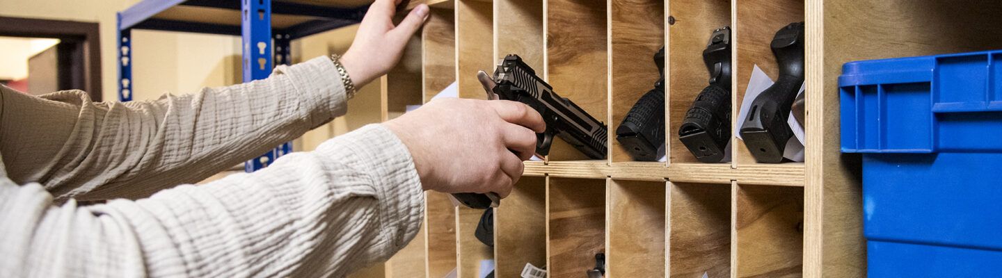 Mitarbeiter entnimmt eine Schusswaffe aus einer Lagerungseinheit