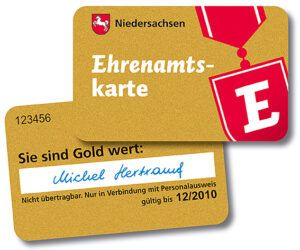 Abbildung einer goldfarbenen Ehrenamtskarte des Landes Niedersachsen mit rotem ‚E‘-Symbol. Auf der Karte stehen der Schriftzug ‚Ehrenamtskarte‘, eine Kartennummer sowie ein Beispielname und ein Gültigkeitsdatum.