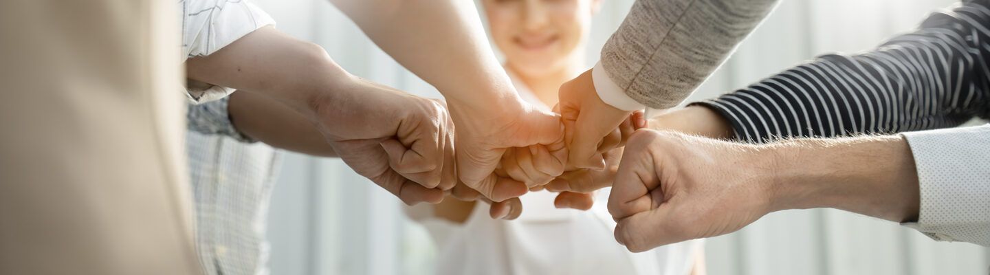 Hände verschiedener Menschen verbinden sich. Symbolbild für Teamwork.