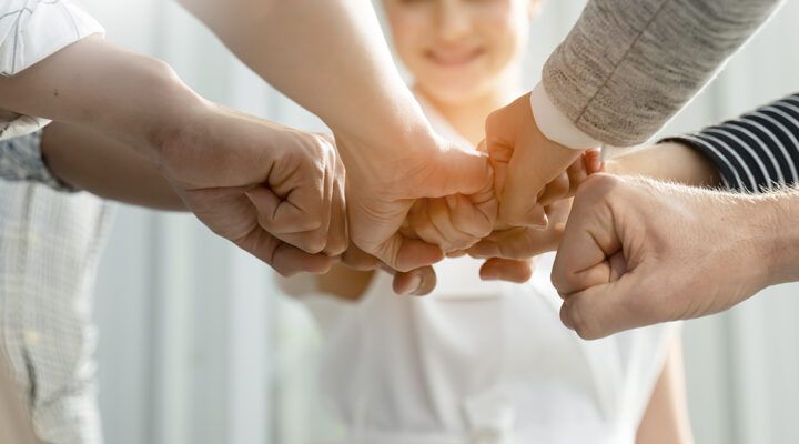 Hände verschiedener Menschen verbinden sich. Symbolbild für Teamwork.