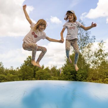 Glückliche Kinder springen auf einen großen Hüpkissen