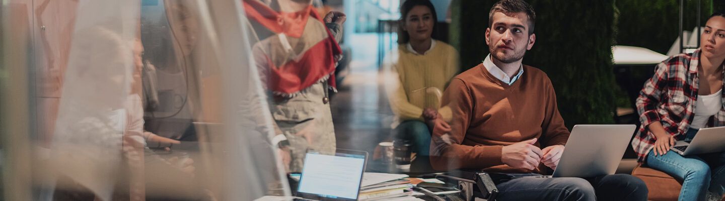 Eine Geschäftsfrau präsentiert ein Projekt vor einem jungen, vielfältigen Team von Menschen in einem modernen Büro