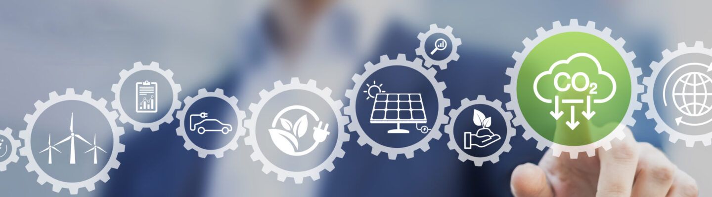 „Eine Person zeigt mit dem Finger auf ein grünes Symbol mit der Aufschrift ‚CO₂‘ und Pfeilen nach unten. Daneben sind Zahnräder mit Icons zu erneuerbaren Energien, Elektromobilität, Nachhaltigkeit und globalem Klimaschutz eingeblendet.