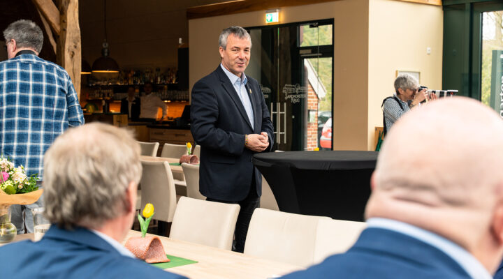 Bundestagsabgeordneter Johann Saathoff steht in einem Veranstaltungsraum und spricht vor mehreren sitzenden Zuhörern; im Hintergrund sind eine Bar sowie eine fotografierende Person zu sehen.