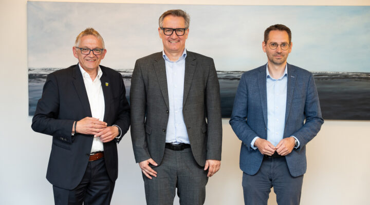 Geschäftsführer der Landkreis Aurich Beteiligungs gGmbH Michael Hohlfeld zusammen mit Landrat Olaf Meinen (links) und Kreisrat Sebastian Smolinski (rechts). Im Hintergrund sieht man ein maritimes Gemälde von der Nordsee.