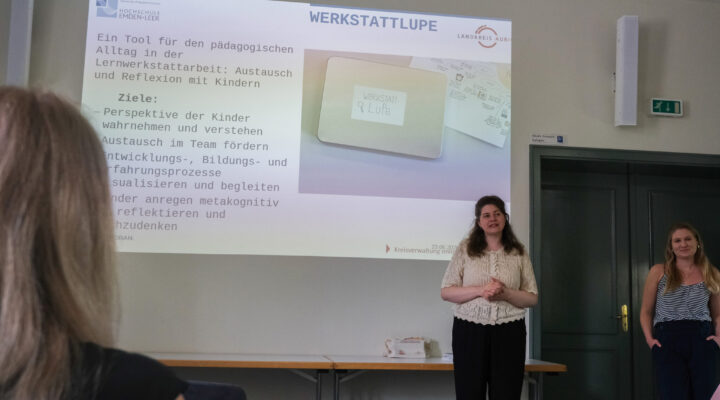 Zwei Referentinnen stellen in einem Veranstaltungsraum die „Werkstattlupe“ vor – ein pädagogisches Werkzeug zur Reflexion in Lernwerkstätten. Hinter ihnen zeigt eine Präsentationsfolie Informationen zum Einsatz des Tools im Kita-Alltag, während die Teilnehmenden aufmerksam zuhören.