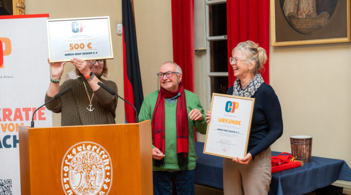 Sonderpreis für „Aurich zeigt Gesicht e. V.“ beim Carl-Osterwald-Preis 2026: Dr. Kerstin Weinbach (links) präsentiert die Auszeichnung mit einem Preisgeld von 500 Euro. Gemeinsam mit ihr freuen sich Jörg Köhler (Mitte) und Heike Pilk (rechts) vom Verein „Aurich zeigt Gesicht e. V.“ über die Würdigung ihres Engagements für Demokratie und gesellschaftlichen Zusammenhalt.